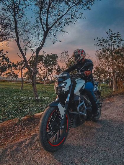A front-facing shot of a rider on a white Dominar during a sunset ride, capturing the beautiful colors of the evening sky.