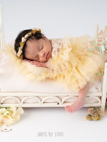 A full view of the setup, with the baby peacefully sleeping on a miniature bed surrounded by flowers. This shows the artistry and care that goes into each newborn session.