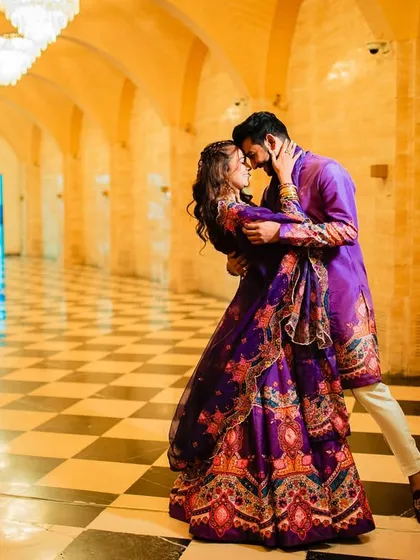 A wide shot showing the bride's full look, with her purple lehenga and beautiful wavy hair.