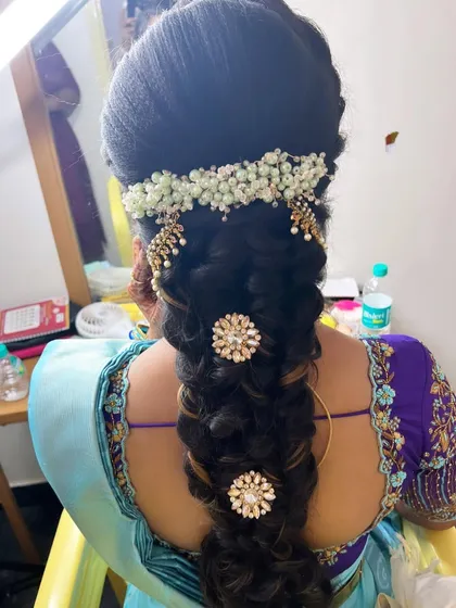 A detailed look at the intricate braid hairstyle created for Anusha's Varapooja, adorned with pearls and floral accessories.