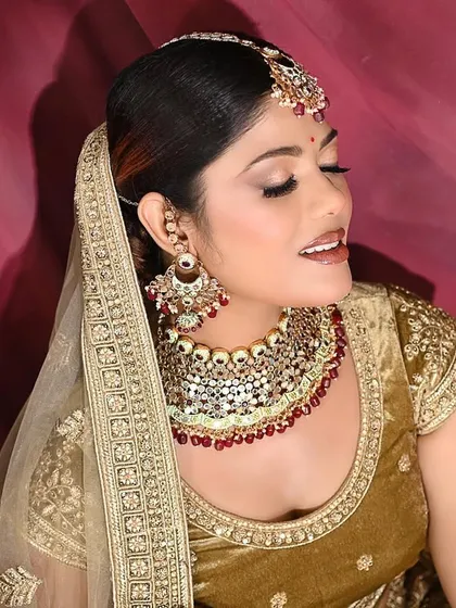 A classic bridal beauty shot. The warm, golden tones of the outfit and jewelry are complemented by the soft lighting, creating a radiant and timeless portrait.