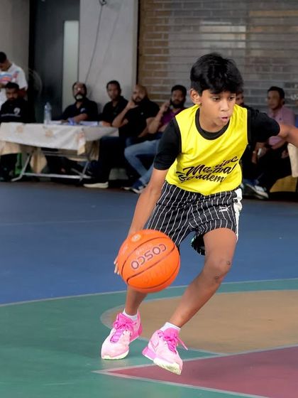 A Maniac player dribbles down the court, pushing the pace against a defender. This highlights the speed and ball control we develop in our young athletes.