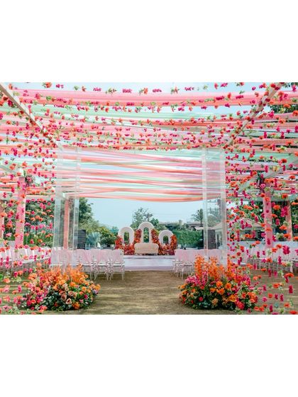 The stunning outdoor decor for the Haldi ceremony, with vibrant floral arrangements and colourful drapes creating a festive atmosphere.