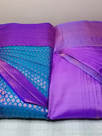 Two beautiful purple sarees, one brocade and one plain, pleated and ready.
