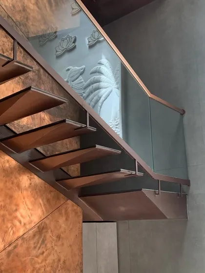 A close-up of the cantilevered stair treads and the glass balustrade, revealing the carved stone frieze beyond. This layering of transparent and solid materials creates visual depth and interest.
