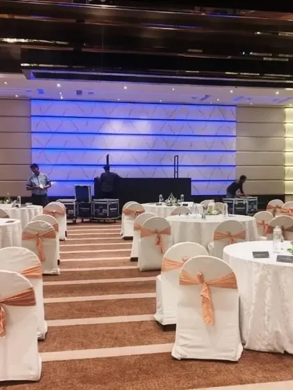 We manage the complete setup for corporate seminars and galas, ensuring a flawless layout. This view shows the ballroom at Radisson Blu, Bangalore, prepared for a business event, with organized seating, clean table arrangements, and stage tech ready for the program.