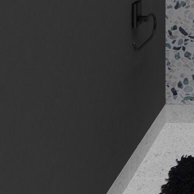 A detail showing the corner of the terrazzo wall and the minimalist black towel hook.