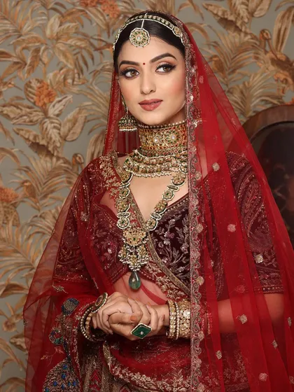 A portrait of a royal Indian bride in a deep red velvet lehenga, her makeup exuding regal elegance.