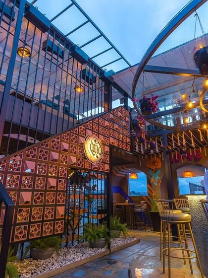 The view from the bar at 'Highdrate,' looking up at the multi-level structure. The design uses terracotta jali blocks and a steel framework to create a visually complex and interesting space, especially as evening approaches.