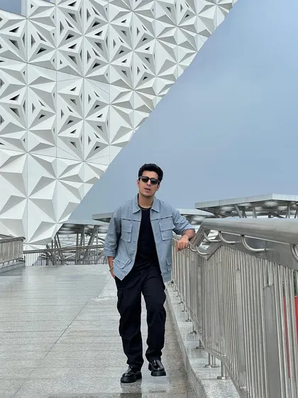 Gagan Arora at the Vivo launch event, styled in a monochromatic look with a statement jacket from Blamblack Clothing against a futuristic architectural background.