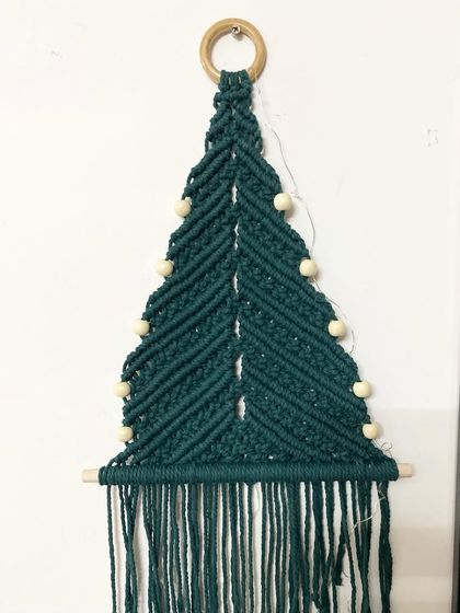 Here is the macrame Christmas tree wall hanging without the lights. It's made with dark green cotton cord and is a beautiful, minimalist decoration.