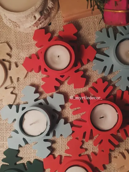 An overhead view of our red and blue Snowflake T-light holders. We love how the colors pop against the rustic burlap, showcasing their simple yet festive design.