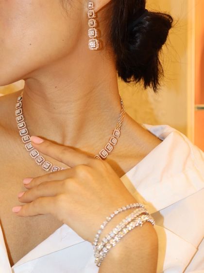 The complete TMJ Diamond Set. This look features a modern square-link diamond necklace, matching drop earrings, and a stack of brilliant tennis bracelets for ultimate sparkle.