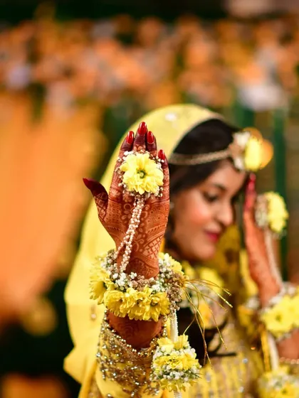 Mehendi da rang! The beautiful, deep red stain on this bride's hands, adorned with fresh floral jewelry.