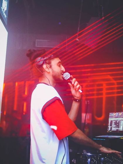 On the mic with red laser beams cutting through the darkness. This shot captures the intensity and focus of being a performer.