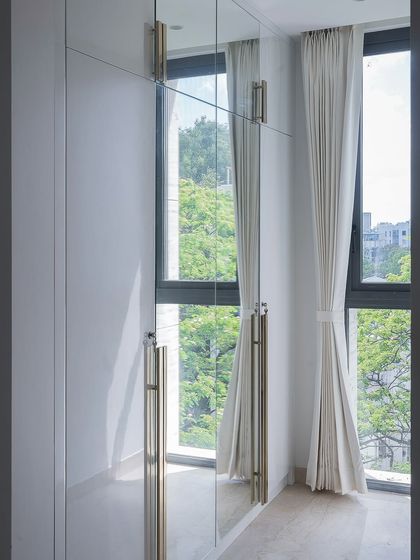 The mirrored wardrobe in this bedroom isn't just for storage; it's a reflection of the room's essence. Custom champagne-toned handles and ample light make the entire space feel larger and brighter.