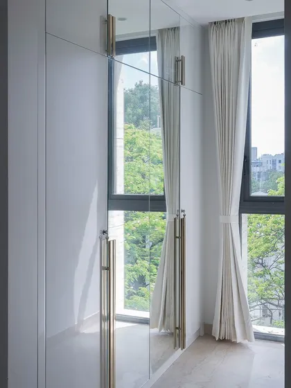 The mirrored wardrobe in this bedroom isn't just for storage; it's a reflection of the room's essence. Custom champagne-toned handles and ample light make the entire space feel larger and brighter.