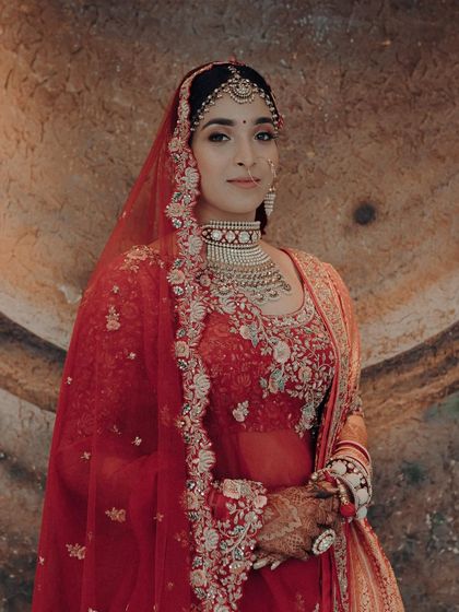 Another stunning portrait of the bride in her red Sabyasachi lehenga. The warm, earthy background makes the red of her outfit even more vibrant and regal.