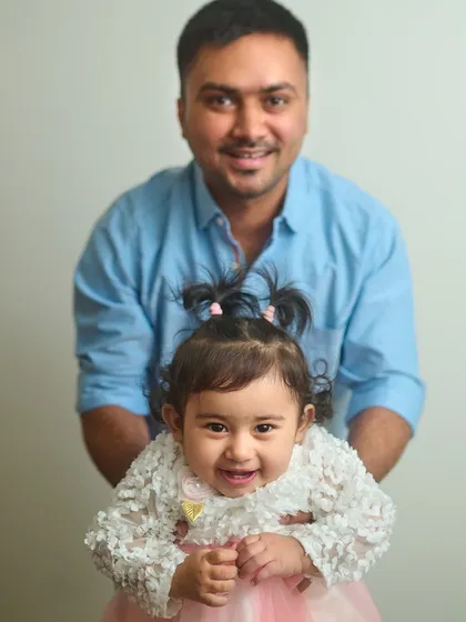 A simple and sweet indoor portrait of a father and his smiling daughter. Even with a plain background, their happy expressions make the photo shine.