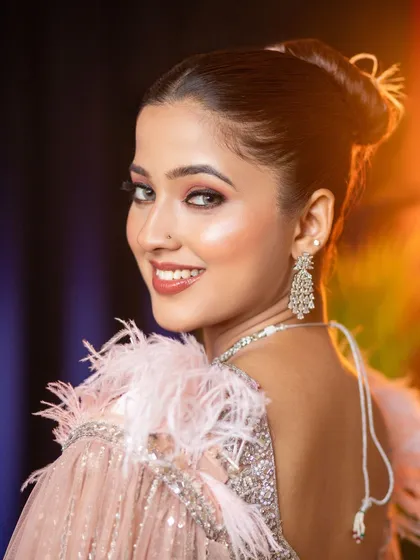 A soft and glamorous party makeup look perfect for a reception or cocktail event portfolio. The model is styled in a sequined pink gown with feather details, complemented by dewy makeup, a subtle pink lip, and sparkling diamond earrings.