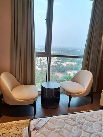A cozy seating nook in a client's bedroom, featuring two of our custom-made low-slung armless chairs and a dark wood side table. This setup creates a perfect spot to enjoy the stunning city view.