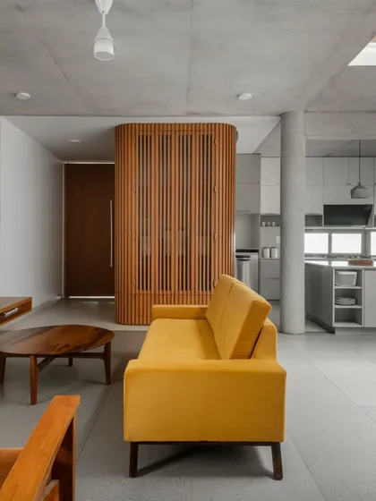 The living, dining, and kitchen areas are arranged in a fluid, open layout. A single concrete column provides structural support while maintaining the visual continuity of the space, making the compact floor plan feel generous.