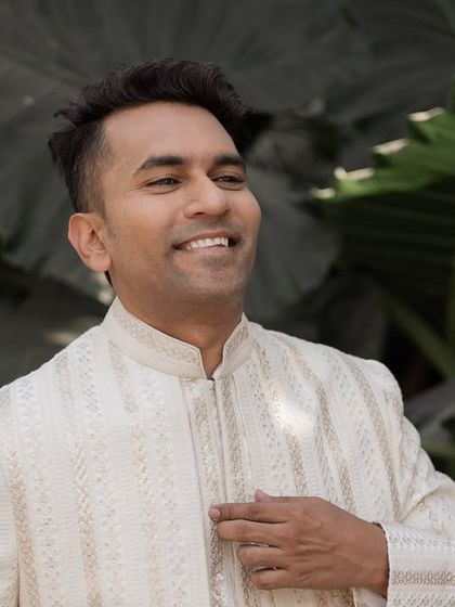 A handsome portrait of the groom, smiling and looking dapper in his wedding attire.