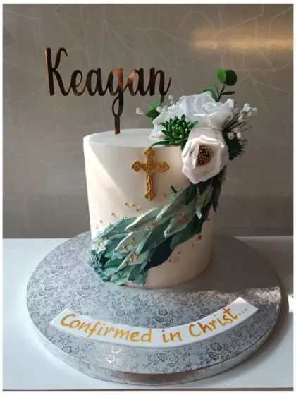 A modern and elegant confirmation cake. The design features a beautiful arrangement of white sugar flowers, succulents, and a gold cross.