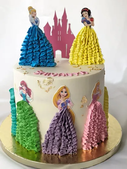 A princess cake with a creative twist. This design features beautiful piped buttercream ruffles to create the princesses' gowns, making the entire cake a work of art.