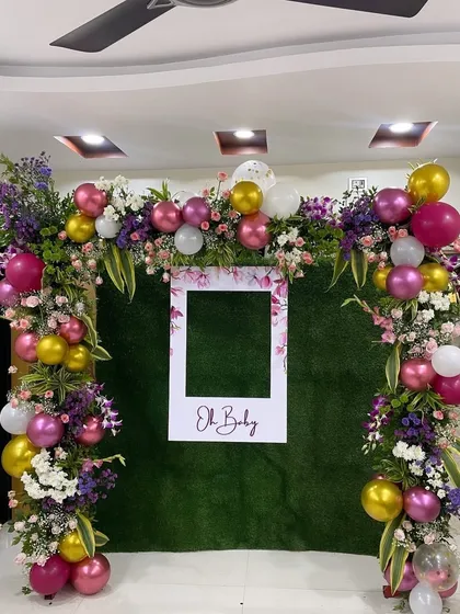 A fun and interactive photo booth I designed for a baby shower. The backdrop features a lush green wall, a floral and balloon arch, and a custom "Oh Baby" polaroid frame.