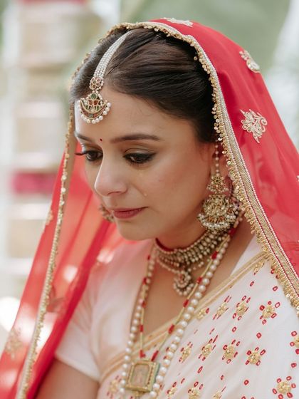 A series of portraits of a bride in a beautiful, traditional white and red saree, capturing her elegance, emotion, and moments with her family.