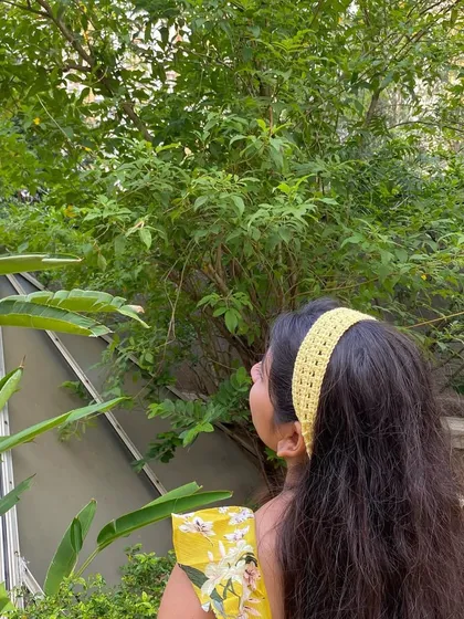 A handmade yellow crochet headband adding a pop of color to a summer outfit. The tie-up design allows for a perfect fit.