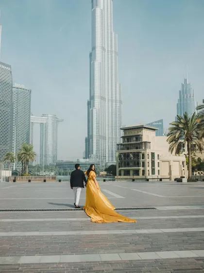 The trail of our mustard yellow gown adds a beautiful finishing touch to this walking shot, creating a sense of movement and elegance in a glamorous city setting.