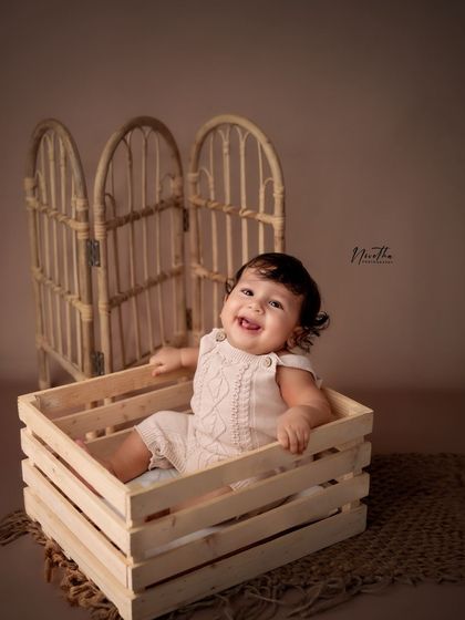 A rustic-themed sitter session with a wooden crate and rattan screen. These simple, natural props create a beautiful, earthy look.
