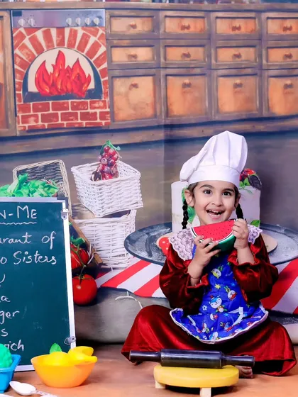 The older sister joins in as a head chef, enjoying a slice of watermelon in our pizzeria-themed shoot.