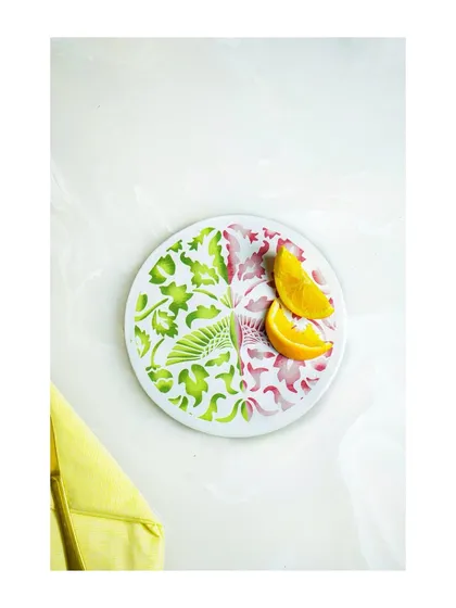 A top-down shot of a plate with a split-color floral design, styled simply with orange slices.