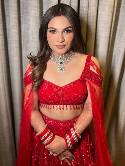 The center-parted wavy hairstyle is a classic choice that allows the bride's sindoor and beautiful features to take center stage.