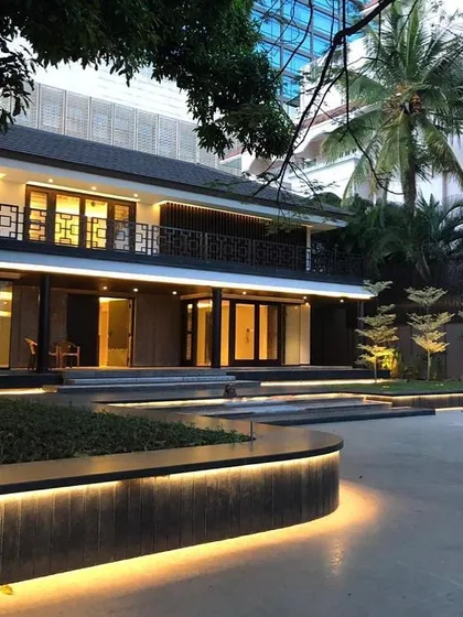 This Bangalore residence features a blend of traditional and modern design elements, with intricate railing details and a stepped landscape design. The curved, illuminated planters guide the approach to the entrance, adding a soft, organic touch.