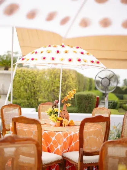 A closer look at the traditional Haldi decor, with custom-printed tablecloths and umbrellas adding a personalized touch to the vibrant orange and yellow theme.