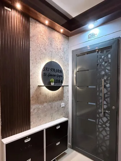 A welcoming and stylish entrance design. We combined a textured wall finish with dark wood fluted panels and a custom, back-lit nameplate to create a sophisticated entryway.