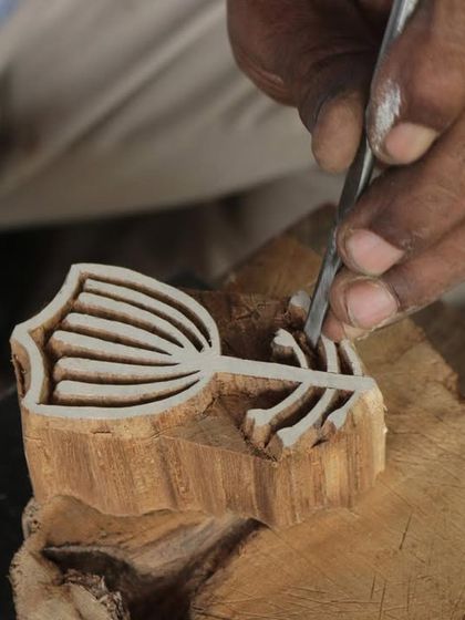 A close-up of a master carver's hands bringing a floral design to life on a teak block. This particular block was created for a collaborative workshop with the Fabric Workshop Museum in Philadelphia.