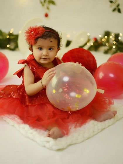 Another beautiful portrait from the first birthday session, with festive balloons and twinkling lights creating a celebratory mood.
