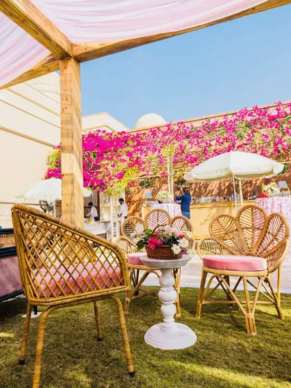 We created a charming seating nook with whimsical cane chairs and pink cushions, set against a wall of vibrant bougainvillea. It’s the perfect spot for an afternoon chat during a sunny Mehendi.