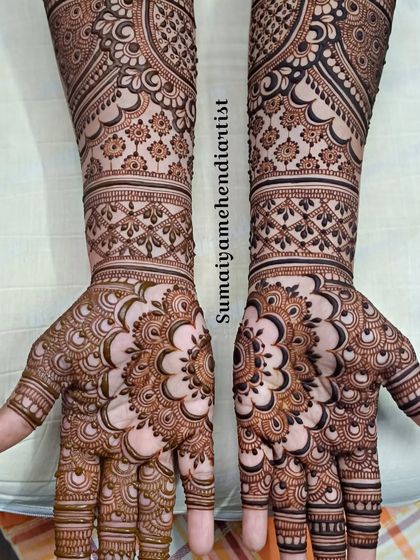 This bridal design features a large, intricate mandala on the palm of each hand. The arms are covered in detailed patterns that create a very full and traditional look.
