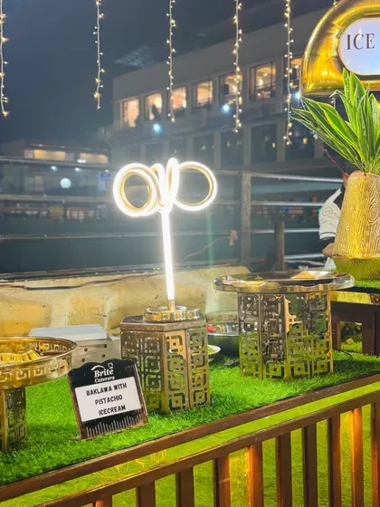 An elegant ice cream counter with gold and green accents, lit by neon and fairy lights.