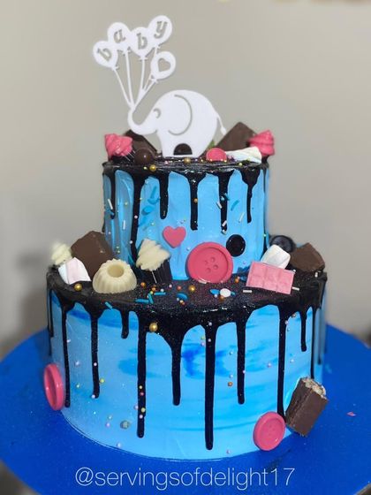 A two-tier baby shower cake with a cute elephant topper. The blue color and chocolate drip make it a modern choice for welcoming a baby boy.