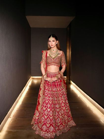 The full view of a stunning red and gold lehenga, styled to feel both regal and comfortable. This is how you own the hallway before you even walk down the aisle.
