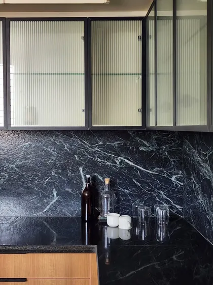 A detail from a contemporary kitchen, where we explored the interplay of textures. The combination of fluted glass, dramatic black marble, and warm wood creates a space that is both highly functional and visually sophisticated.