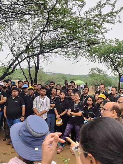 Our expert holds up a native sapling to show the large, enthusiastic team from Colt Technology Services before they begin their planting.