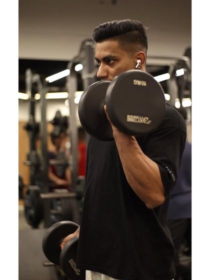 A member performs alternating dumbbell bicep curls, focusing on proper form to maximize muscle growth and avoid using momentum.